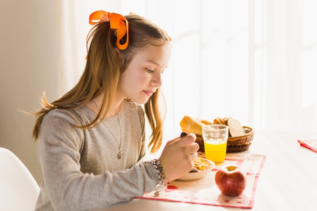 Vista laterale di una ragazza che mangia prima colazione sana fresca