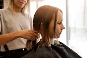 Free photo side view girl getting hair styled at salon