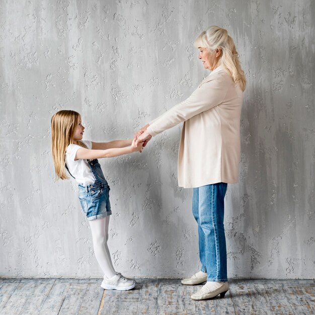 Side view girl and grandma holding hands