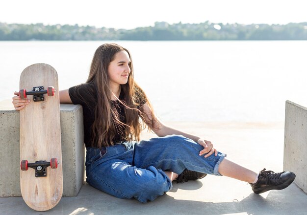 Side view girl holding her skateboard