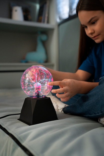 Free photo side view girl interacting with a plasma ball