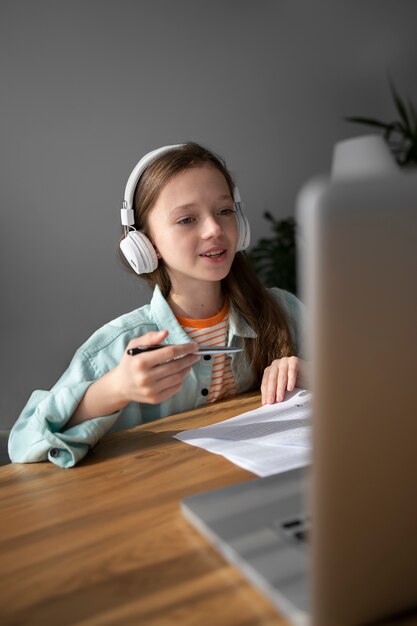 Ragazza di vista laterale che impara con il computer portatile