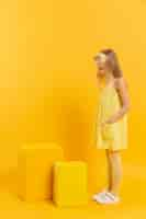 Free photo side view of girl looking at yellow stools with copy space