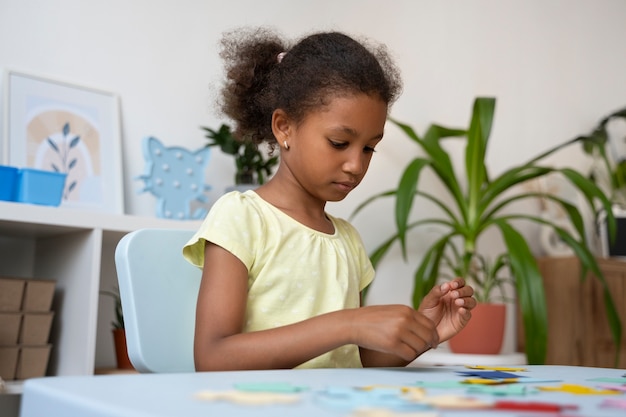 Side view girl making puzzle at table