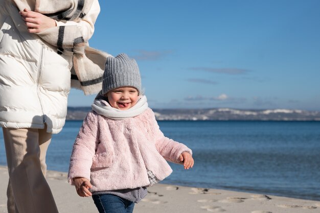 Foto gratuita ragazza e madre di vista laterale che camminano sulla spiaggia