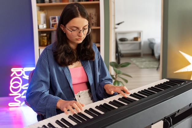 Бесплатное фото Вид сбоку девушка играет на пианино дома