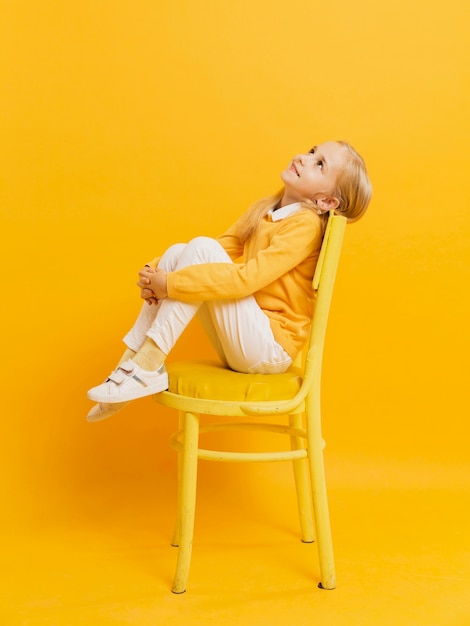 Side view of girl posing on chair while looking up