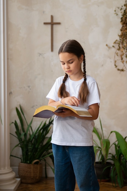 Foto gratuita ragazza di vista laterale che legge la bibbia alla scuola domenicale