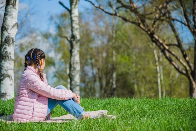 Free photo side view of girl sitting on grass