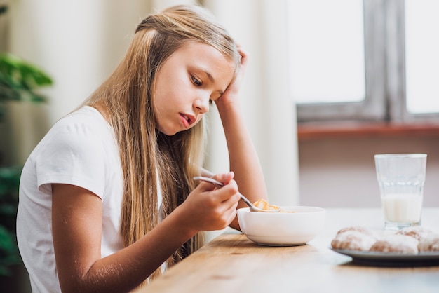 穀物のスプーンを取る側ビュー女の子