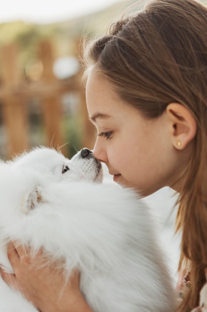 Side view girl touching noses with her dog
