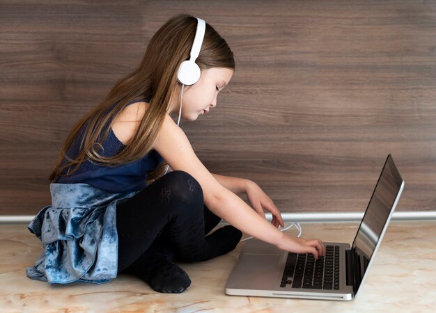 Side view of girl using laptop with headphones
