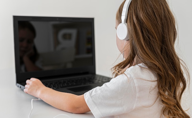 Foto gratuita vista laterale della ragazza che utilizza computer portatile con le cuffie