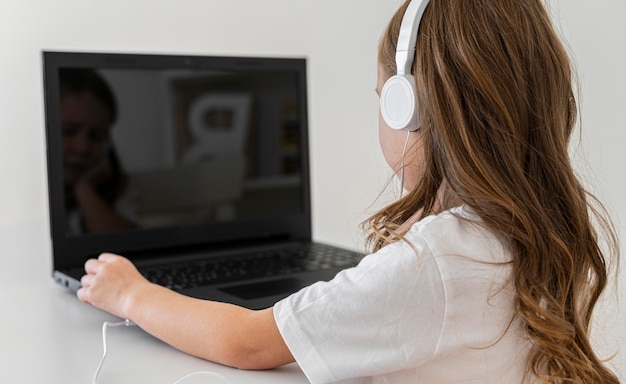 Vista laterale della ragazza che utilizza computer portatile con le cuffie