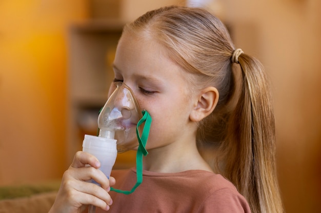 Free photo side view girl using nebulizer