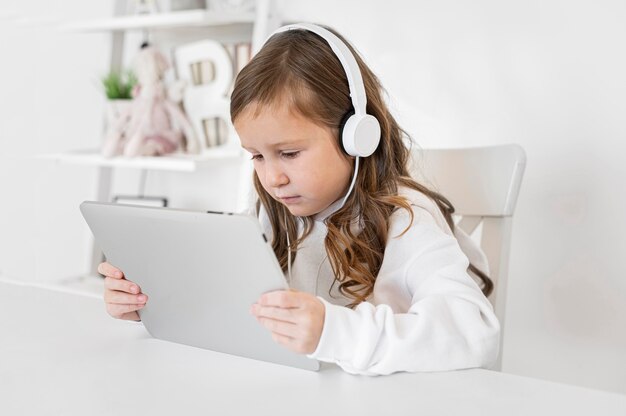 Side view of girl using tablet with headphones