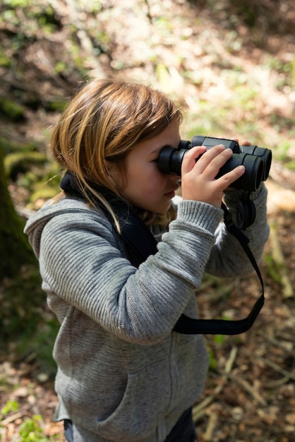 Foto gratuita ragazza di vista laterale con il binocolo