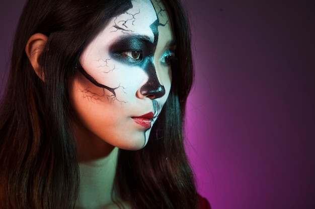 Side view of girl with makeup and halloween mask