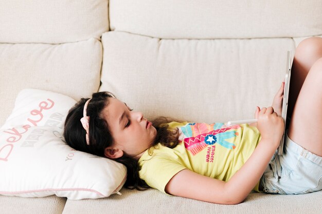 Side view girl with tablet sitting on the couch