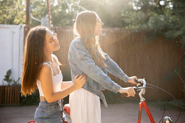 Side view girlfriends riding bike together