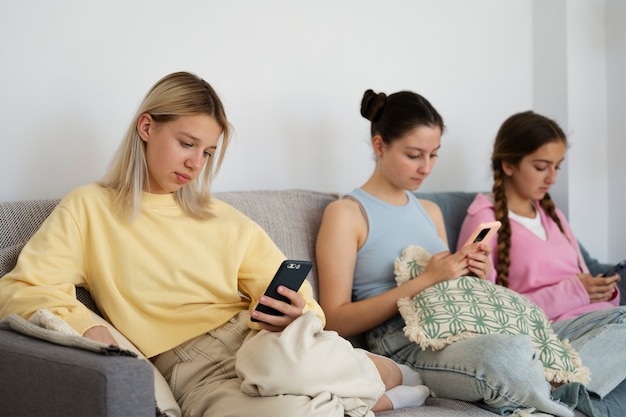 Side view girls on couch with smartphones