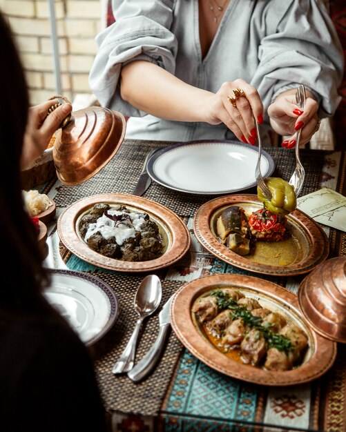 Side view girls eat dolma and cabbage rolls with yogurt