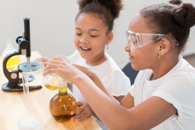 Free photo side view of girls experiments chemistry at home