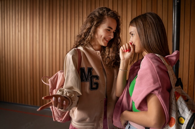 Foto gratuita ragazze di vista laterale che spettegolano a scuola