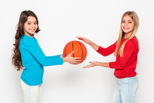 Free photo side view girls playing with basketball ball