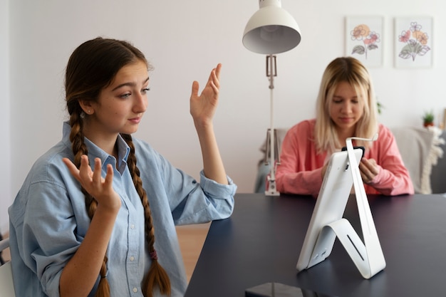 Side view girls with devices indoors