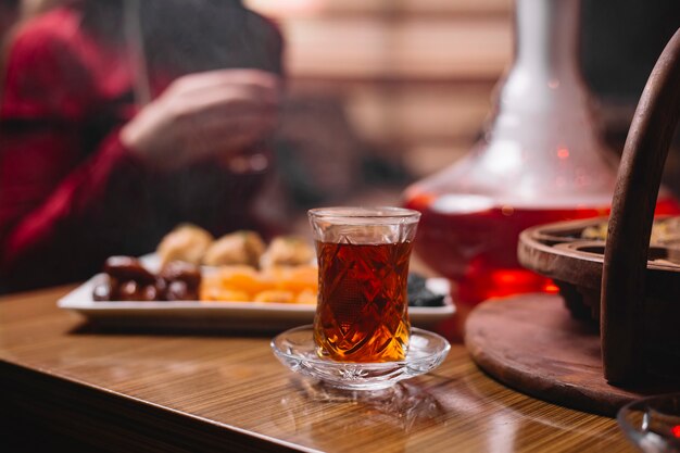 Side view a glass of armudu tea with dried fruits