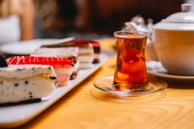 Side view glass of tea with cakes