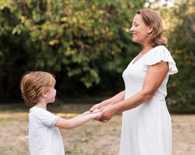 Free photo side view grandma and kid holding hands