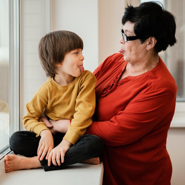 Side view of grandmother and grandson playing and sticking their tongues out