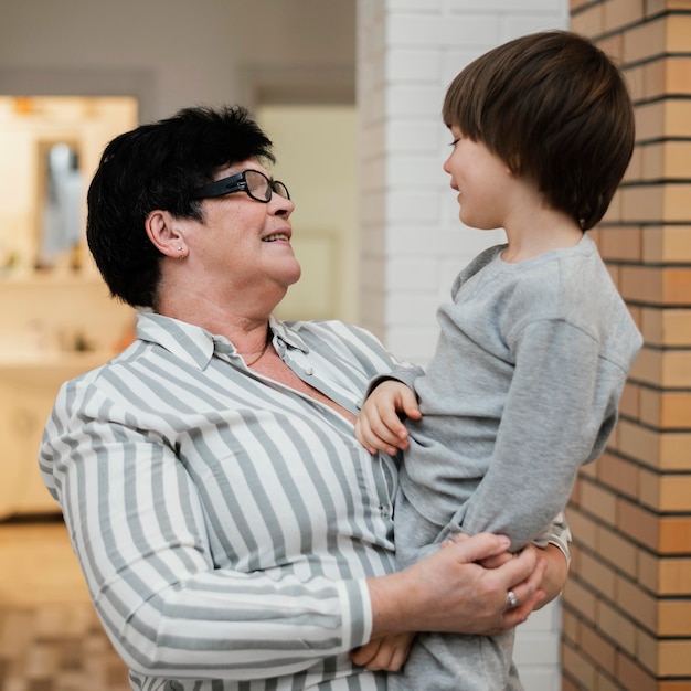 Free photo side view of grandmother holding her grandson