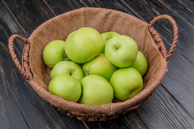 side view of green apples in basket on wooden