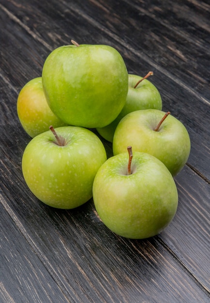 Free photo side view of green apples on wooden background