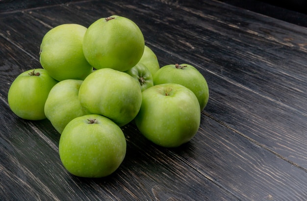 Вид сбоку зеленых яблок на деревянной поверхности с копией пространства