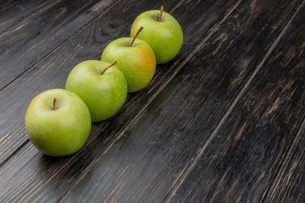 Side view of green apples on wooden surface