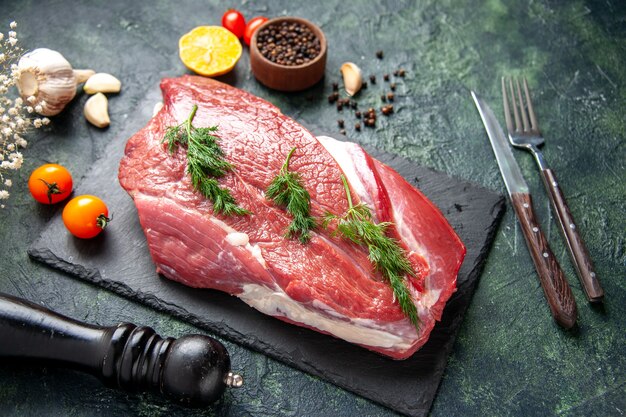 Side view of green on fresh red raw meat on cutting board and pepper lemon black hammer flower on green black mix color background