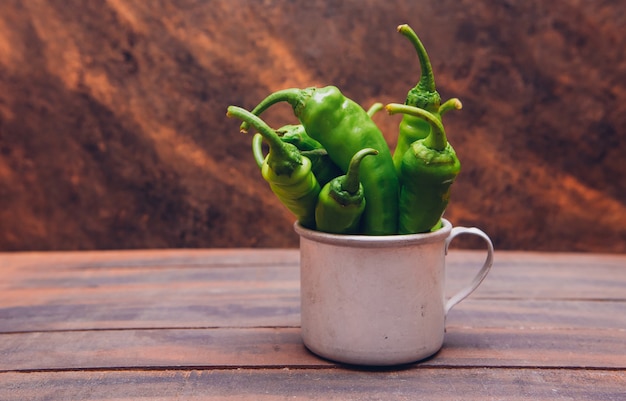 Side view green korean peppers in cup on wooden table