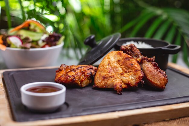 Side view grilled chicken fillet with sauce and rice garnish on a tray