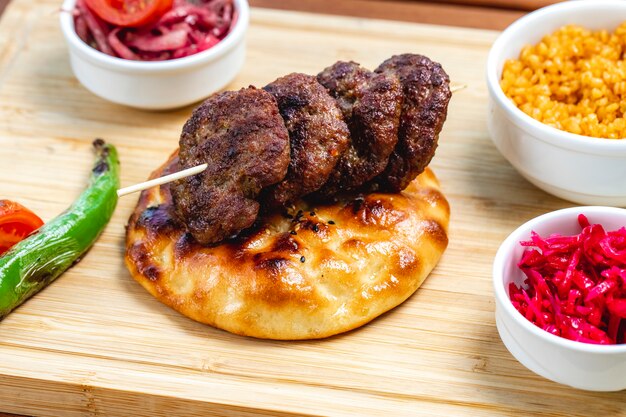 Side view grilled meat cutlets on bread with hot green pepper tomato and pickled cabbage on the table