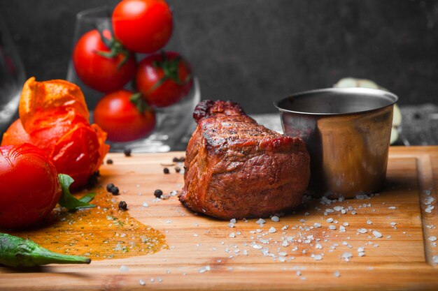 Side view grilled meat with tomato and paper and sauce in steak board