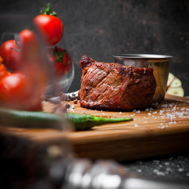 Side view grilled meat with tomato and sauce in steak board