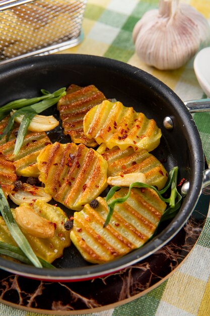 Side view grilled potatoes with black pepper greens and garlic on the tablecloth