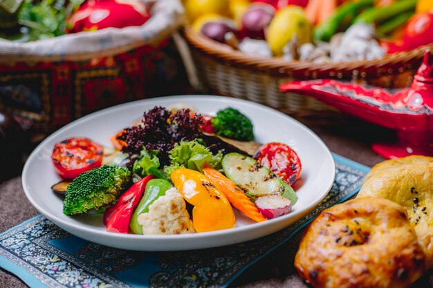 그릇에 토마토 브로콜리 아보카도 피망과 콜리 플라워와 구운 야채 샐러드의 측면보기