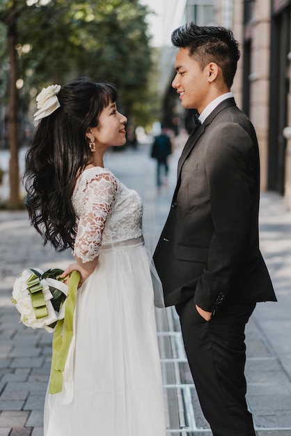 Vista laterale dello sposo e della sposa in posa in mezzo alla strada