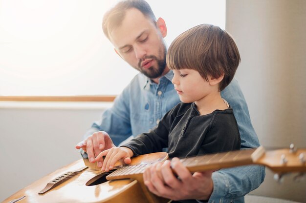 自宅で子供にレッスンを与えるギターの先生の側面図