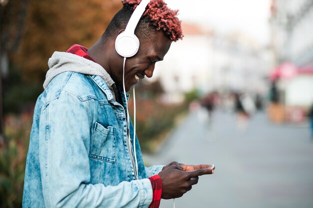 Side view guy with headphones and smartphone